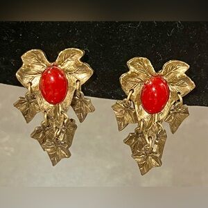 Vintage clip-on earrings featuring a red lucite cabochon and Gold tone leaves